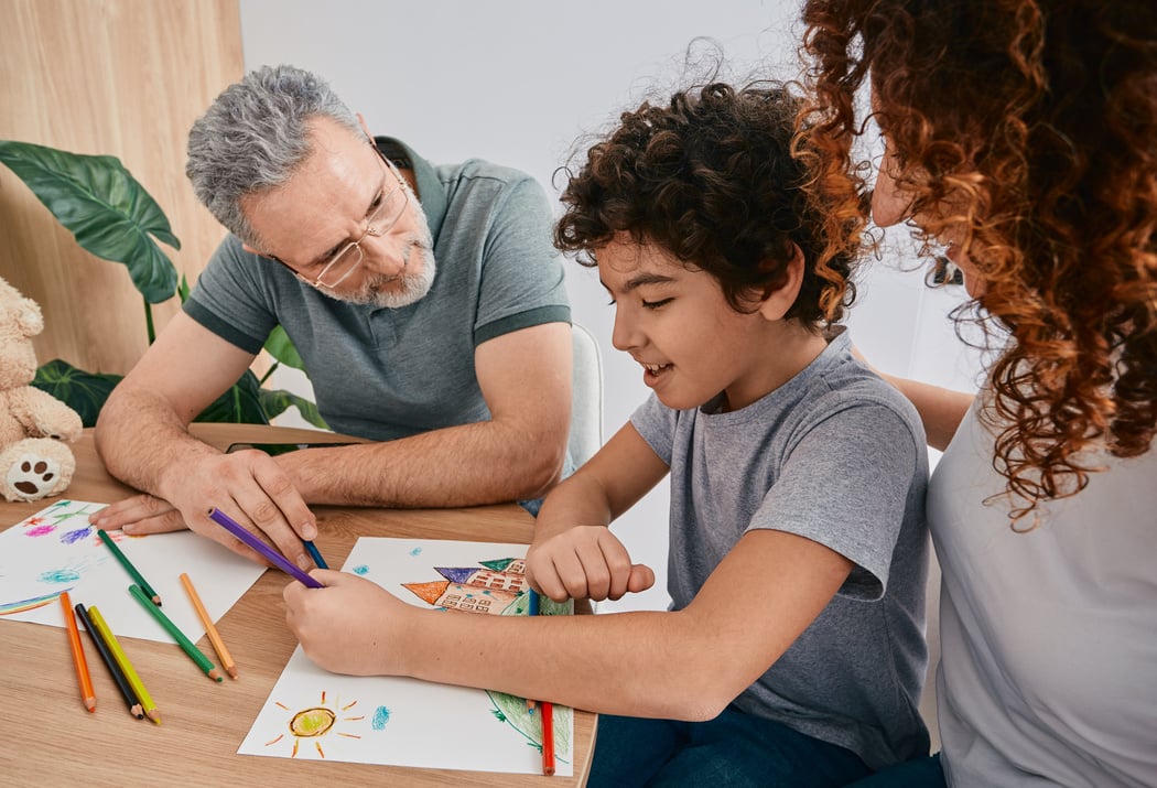 Curly male child with mother during art therapy with psychologist counsel at psychologist's office. Children's art therapy