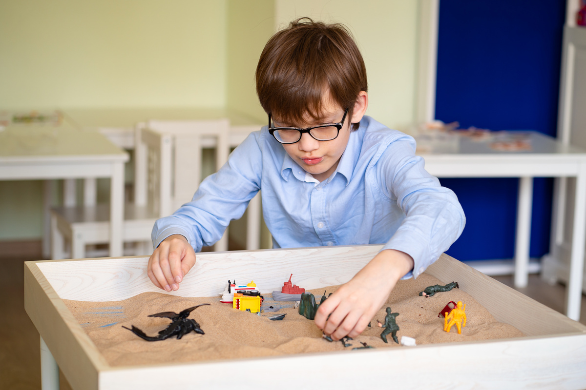 boy glasses is sand therapy on table with light